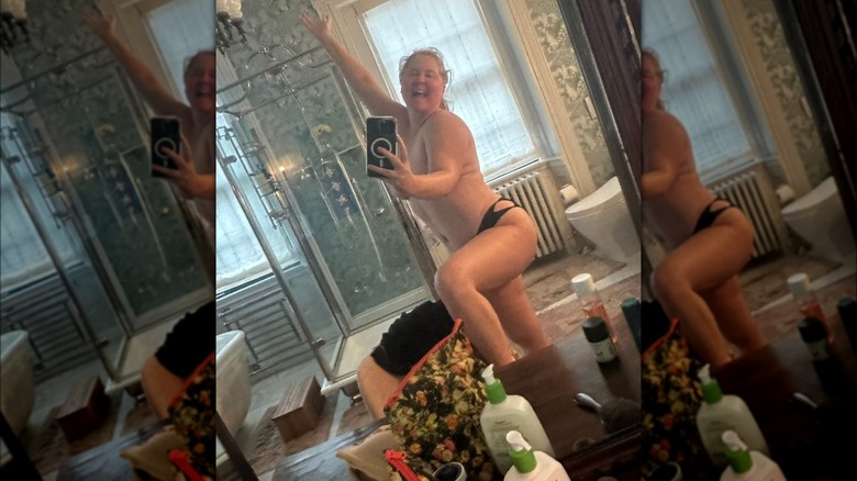 Amy Schumer taking a selfie topless with an arm covering her chest