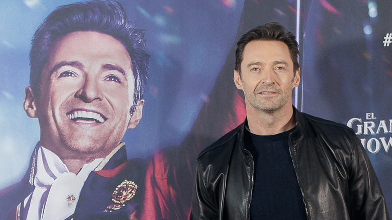 Hugh Jackman posing next to poster of his face