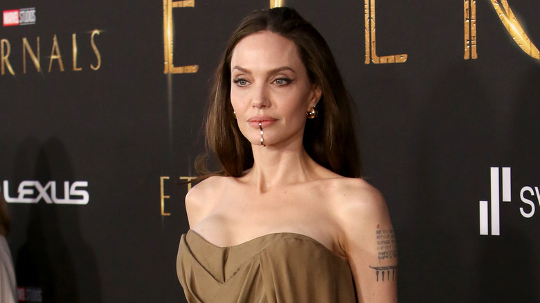 Angelina Jolie at an event, posing with chin cuff