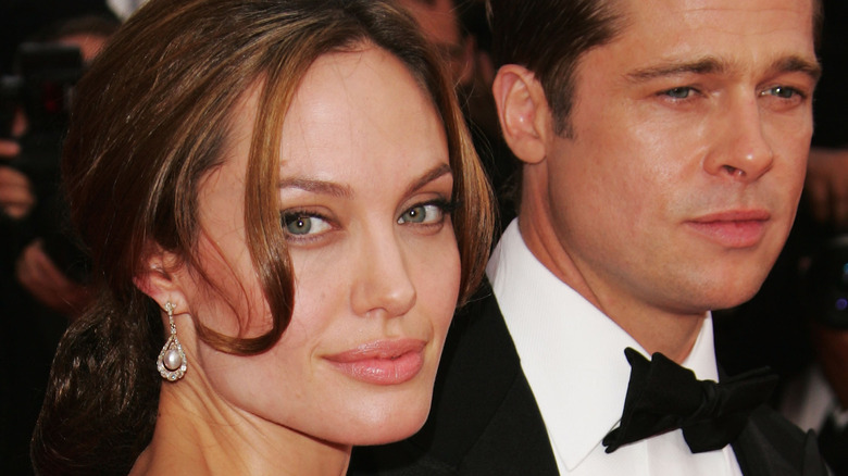 Angelina Jolie smiles at camera Brad Pitt stares ahead