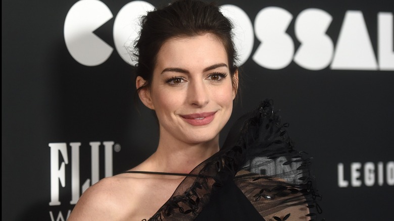 Anne Hathaway smiling in a black dress