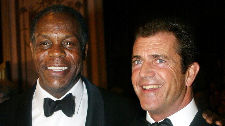 Danny Glover and Mel Gibson smiling in tuxedos