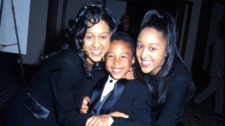 Tia Mowry and Tamera Mowry hugging Tahj Mowry