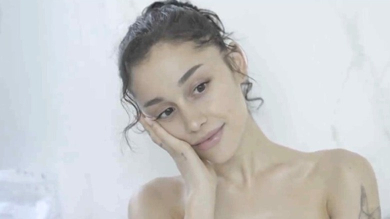 Ariana Grande with curly hair pulled up in ad for her body care products