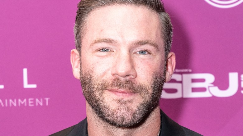 Julian Edelman standing in front of a purple wall, smiling