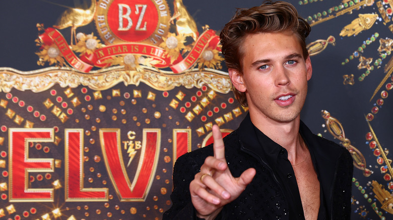 Austin Butler pointing in front of "Elvis" poster