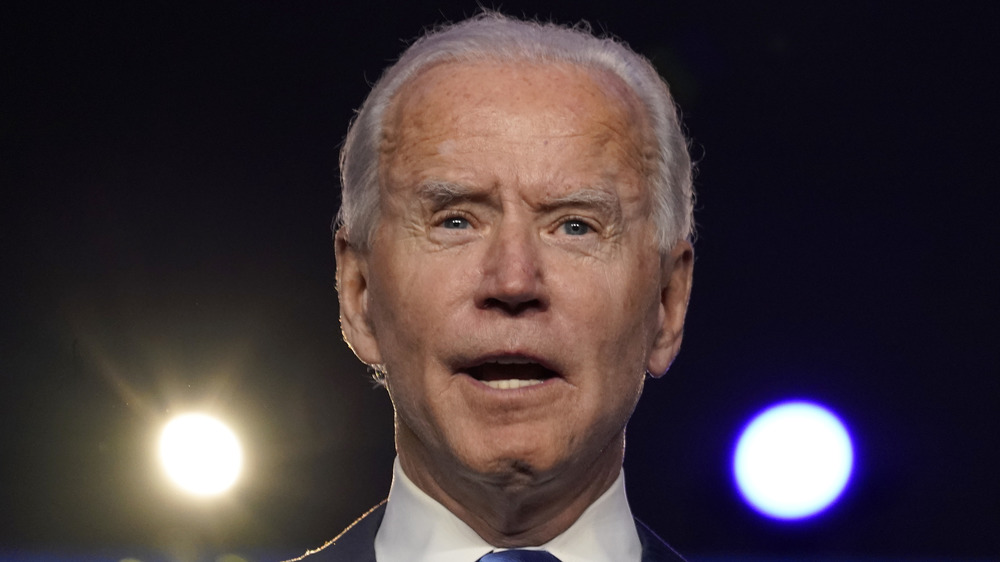 Joe Biden speaking onstage in front of bright lights