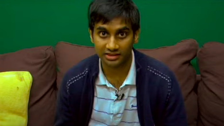 Aziz Ansari seated, looking at camera