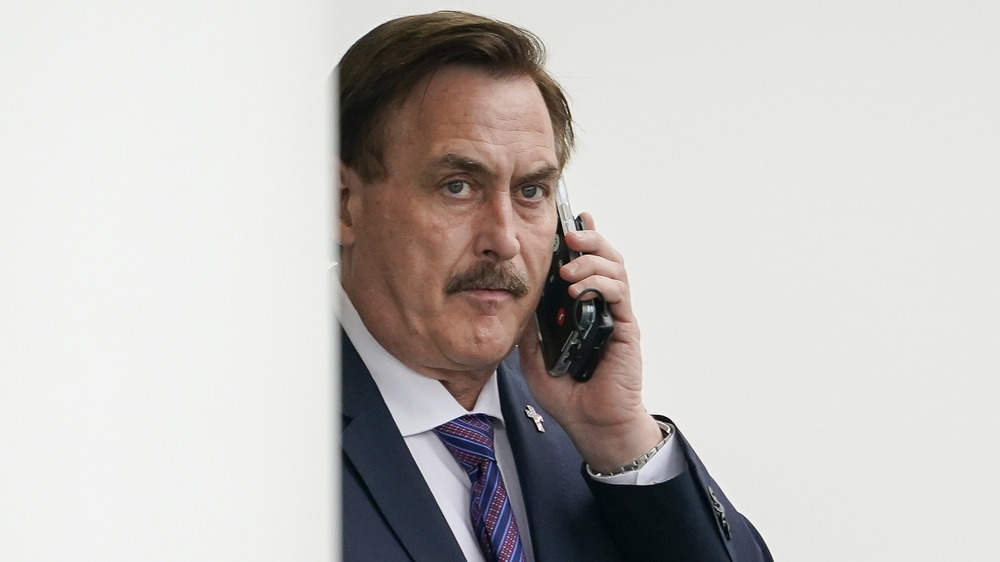 Mike Lindell, on the phone, looking serious, in a suit