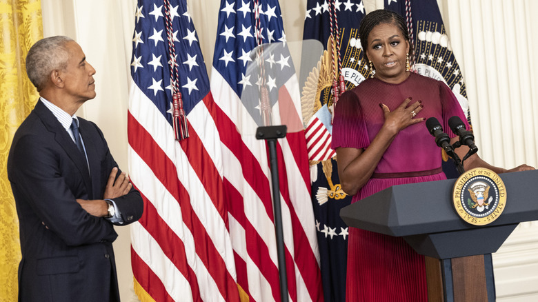 Barack watching Michelle Obama speak at podium