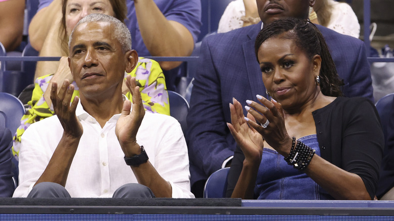 Barack and Michelle Obama frowning and clapping