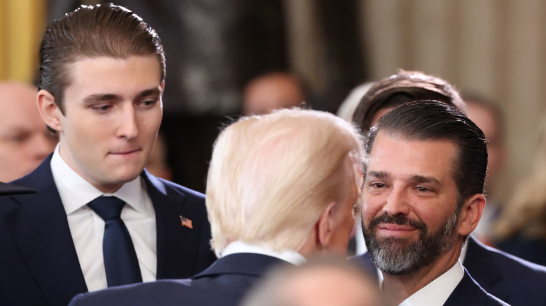 Barron Trump and Donald Trump Jr. shaking hands with Donald Trump