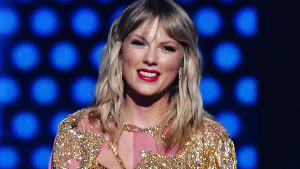 Taylor Swift smiling wearing a Santa hat, choker necklace and red lipstick