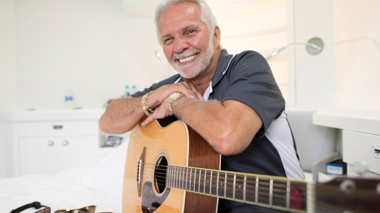 Captain Lee Rosbach smiling with guitar