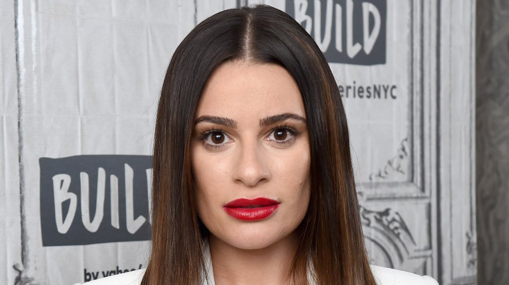 Lea Michele in a white suit and red lipstick, looking shocked