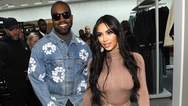 Kanye West smiling behind Kim Kardashian