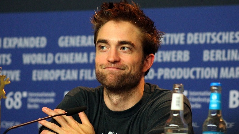 Robert Pattinson grinning behind mic