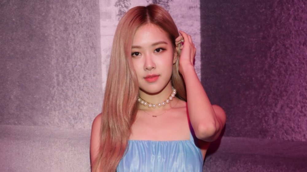 Rosé of BLACKPINK posing with a small smile while fixing her hair