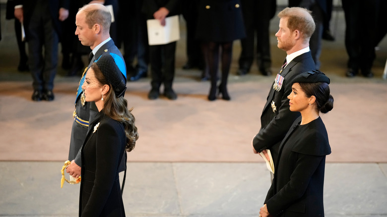 Kate Middleton, Prince William, Prince Harry, and Meghan Markle stand during a funeral procession for Queen Elizabeth II