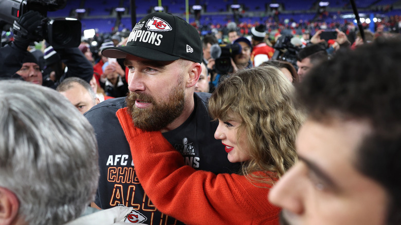 Taylor Swift with her arms wrapped around Travis Kelce