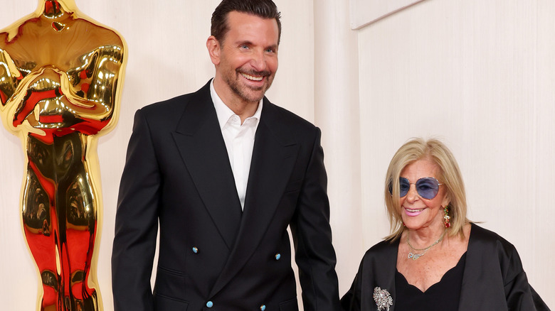 Bradley Cooper and his mother stand near Oscar statue