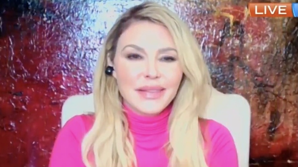 Brandi Glanville, on video chat with The Morning Show, 2021, blond hair down, pink sweater, puffy face and lips