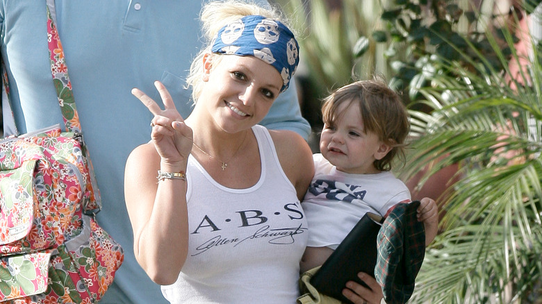 Britney Spears giving a peace sign while holding her son