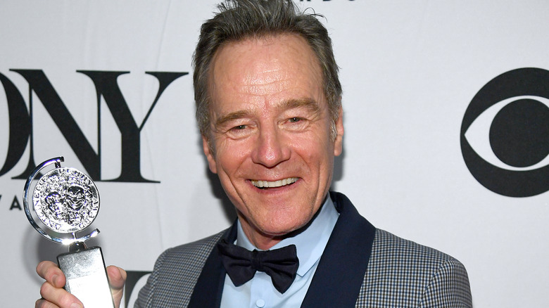 Bryan Cranston smiling and holding Tony award