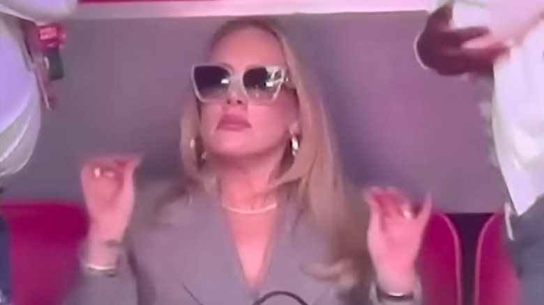 Adele with hands up, wearing sunglasses