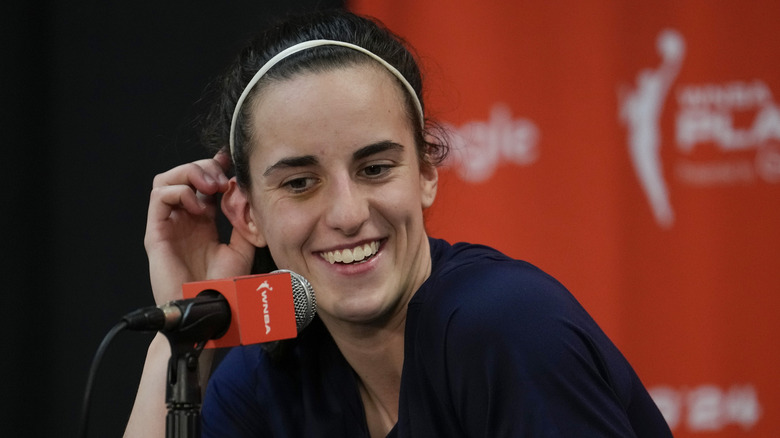 Caitlin Clark smiling in front of a microphone