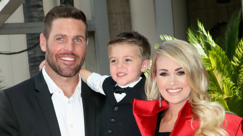 Mike Fisher and Carrie Underwood posing with their son Isaiah on the Walk of Fame.