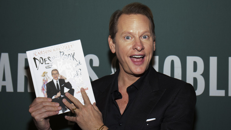 Carson Kressley posing with a copy of his book