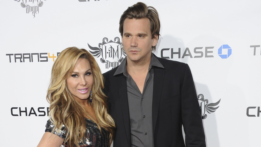 Adrienne Maloof and Sean Stewart hugging on a red carpet 