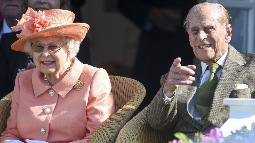 The Queen in a salmon-colored ensemble and Prince Philip, pointing