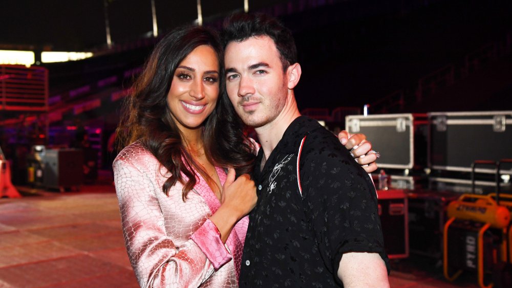 Danielle Deleasa in a pink blazer, hugging Kevin Jonas