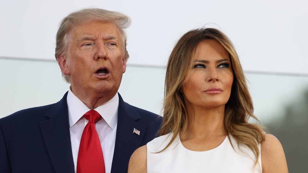 Donald Trump speaking next to Melania Trump, looking away