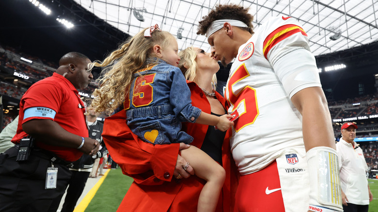 Patrick kissing Brittany Mahomes while holding their child