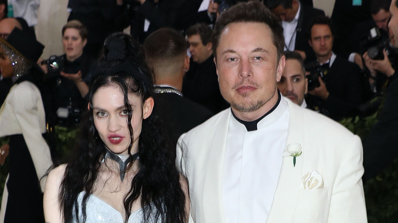 Elon Musk with Grimes posing