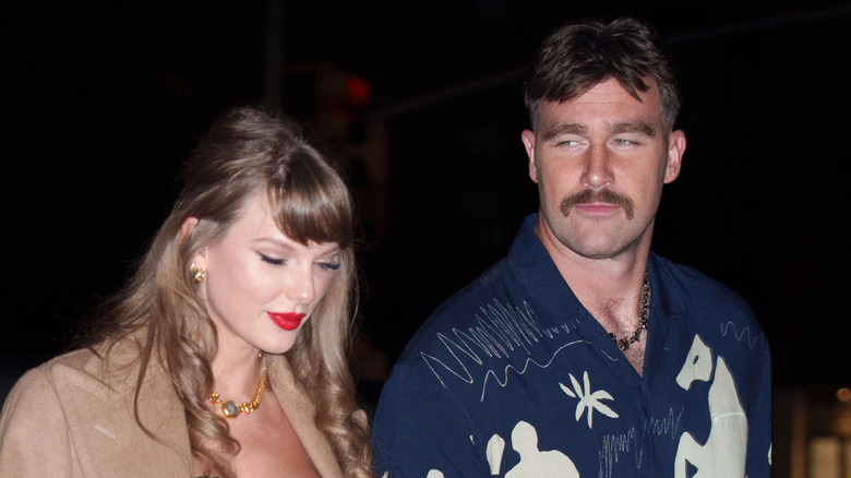 Taylor Swift wearing bustier walking beside Travis Kelce with mustache in NYC