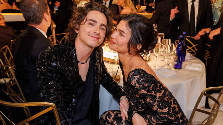 Kylie Jenner leaning toward Timothée Chalamet at their table at the 2024 Golden Globe Awards