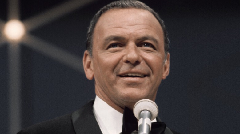 Frank Sinatra grinning in tuxedo on stage