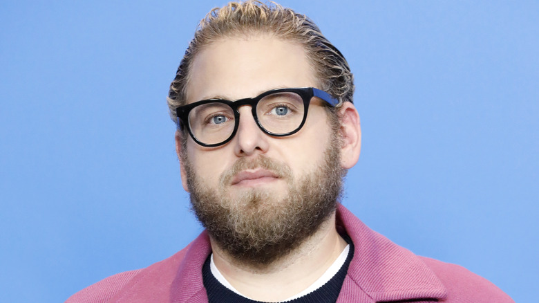 Jonah Hill wearing glasses with a blue background