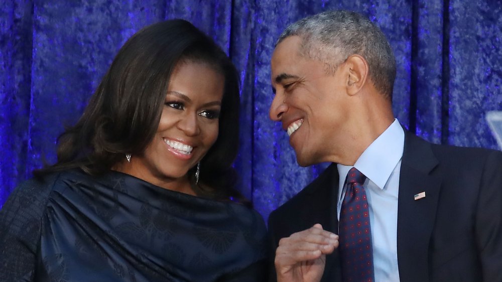 Michelle Obama laughing while Barack Obama smiles at her