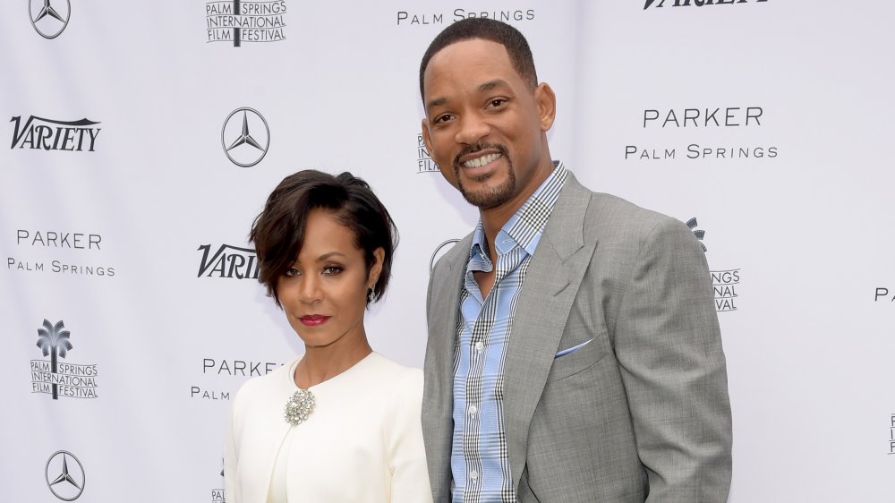 Jada Pinkett Smith and Will Smith posing in front of a red carpet wall