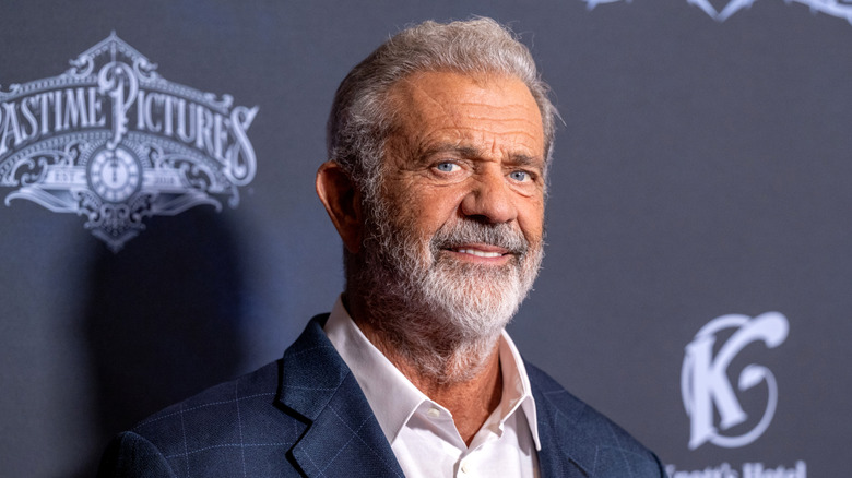 Mel Gibson wearing a blue suit jacket and white collared shirt