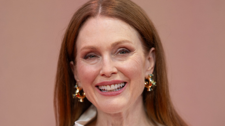 Julianne Moore smiling and posing in a red gown at a red carpet event in 2024