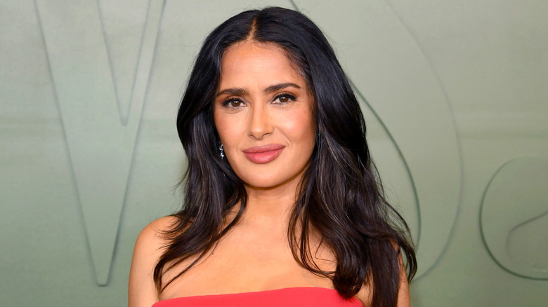 Salma Hayek posing in a red gown at an awards show in 2024