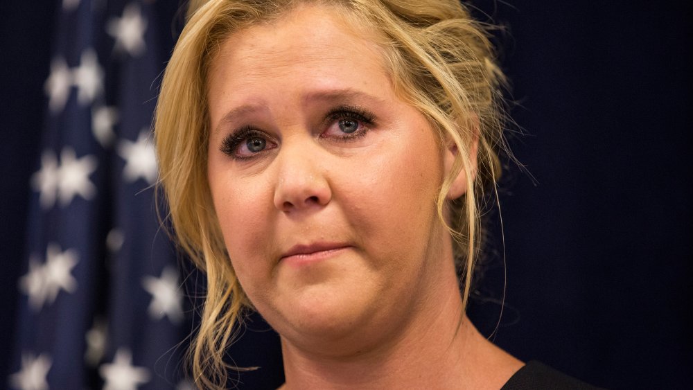 Amy Schumer looking emotional at a press conference with U.S. Senator Chuck Schumer 