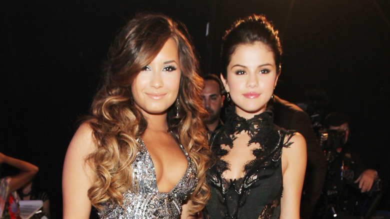 Demi Lovato in silver dress and Selena Gomez in black dress