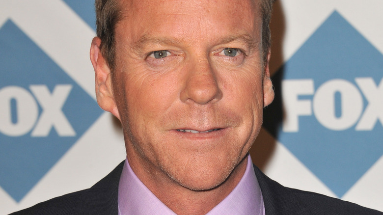 Kiefer Sutherland on red carpet in purple shirt and suit